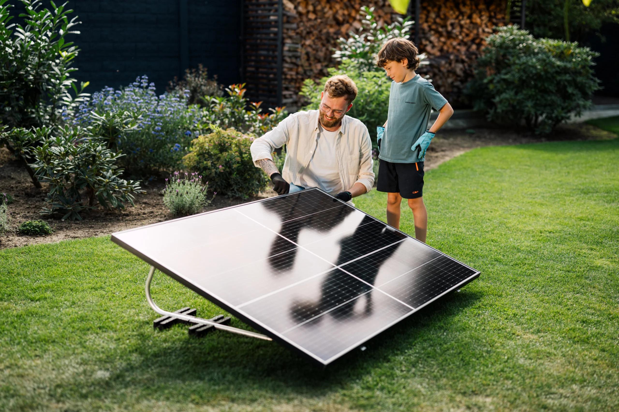 Vater und Sohn stehen über Balkonkraftwerk im Garten